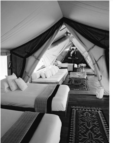 a tent with two beds and a table in it at Noé Nomade in Sidi Bou Othmane