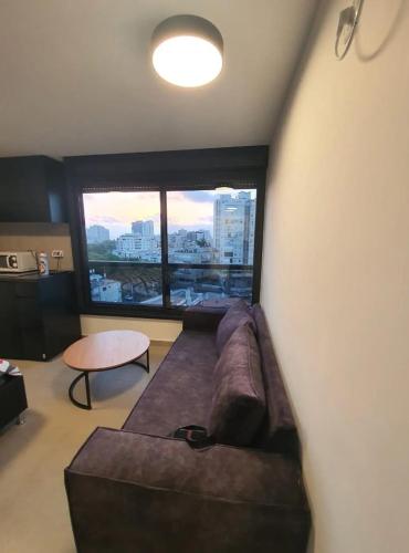 - un salon avec un canapé et une grande fenêtre dans l'établissement Bograshov Modern 2BR Apartment, à Tel Aviv