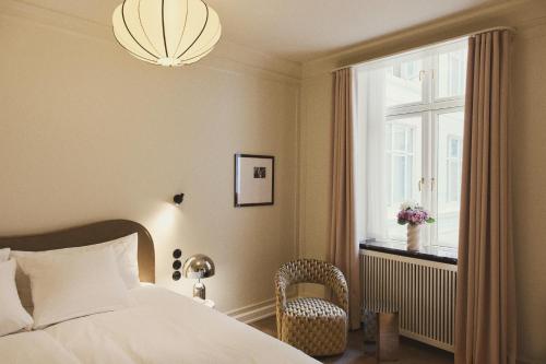 a bedroom with a bed and a window and a chandelier at Hotel Bella Grande in Copenhagen