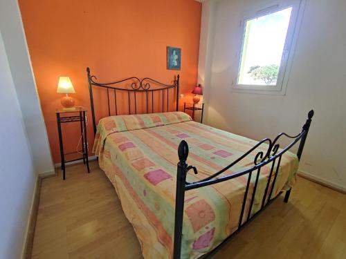 une chambre avec un lit avec un mur orange dans l'établissement Villa 30, La Palmeraie au village naturiste, au Cap d'Agde