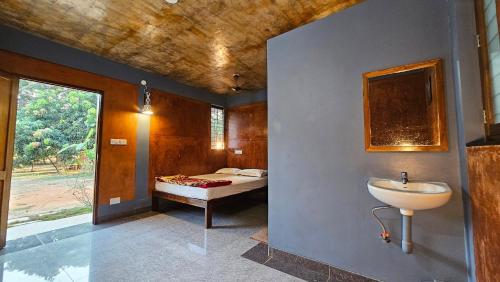 a bathroom with a sink and a bedroom with a bed at Time Travellers Farm Stay in Auroville