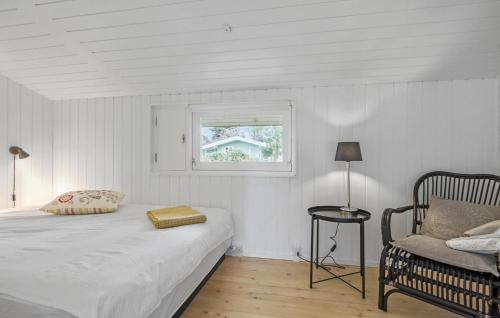 3 Bedroom Cozy Home In Gilleleje في جيليليه: غرفة نوم بسرير ونافذة وكرسي