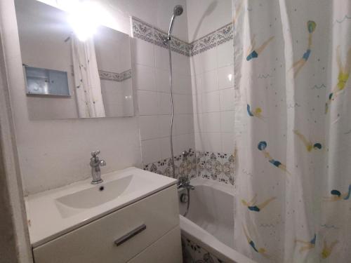 une salle de bain avec un lavabo et un rideau de douche dans l'établissement Villa 30, La Palmeraie au village naturiste, au Cap d'Agde