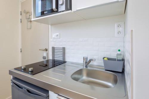 une cuisine avec un évier et un plan de travail dans l'établissement Appartement 2 proche de la gare et centre ville, à Amiens