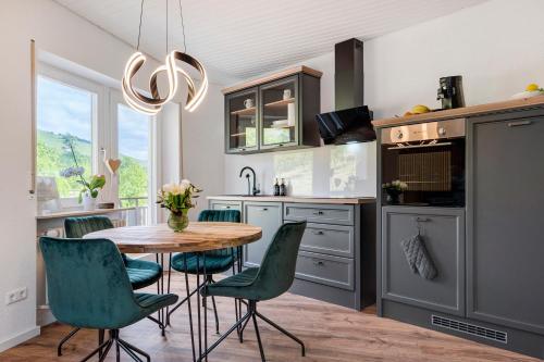 a kitchen with a wooden table and green chairs at Dasensteinblick in Kappelrodeck