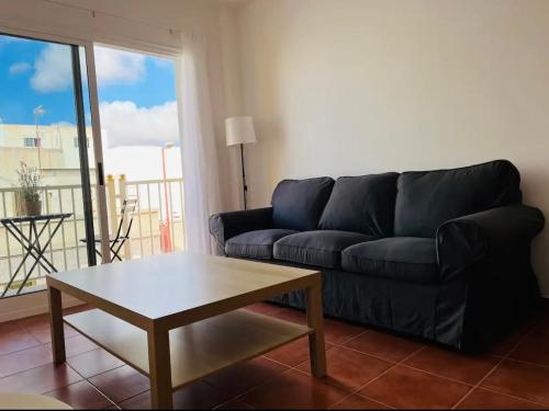 Sala de estar con sofá negro y mesa de centro en Apartamento Ophelia, en Puerto del Rosario