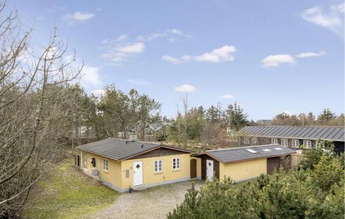 a small yellow house in the middle of a forest at Beautiful Home In Blåvand With Wifi in Blåvand