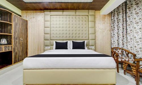 um quarto com uma cama grande e uma cadeira em FabHotel Prime Grand Ali em Srinagar