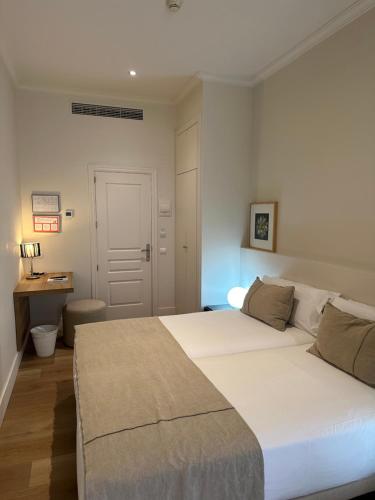 a bedroom with a large white bed and a desk at Hostal Goya in Barcelona