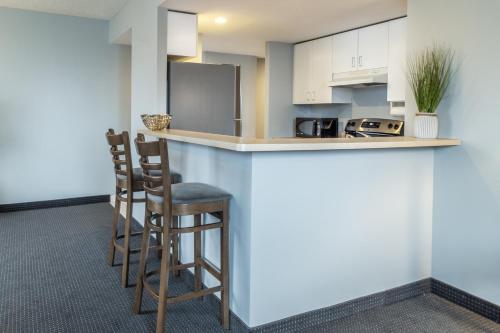 a kitchen with a counter and two stools at a bar at Hôtel Saint-Laurent Montréal in Montréal