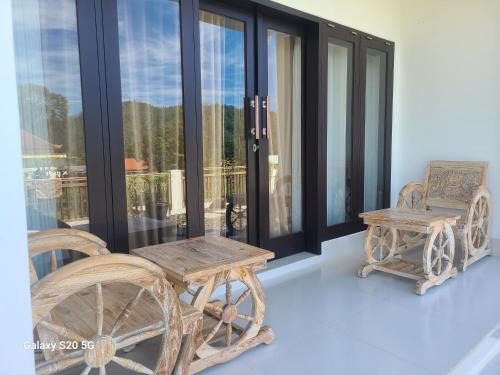 a porch with a wooden table and chairs and windows at Batur lake view in Kintamani