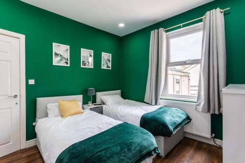 a green bedroom with two beds and a window at 4 Bed House Contractor & Leisure in Preston