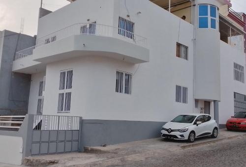 ein weißes Gebäude mit einem davor geparkt in der Unterkunft Estúdio Vieira in Praia