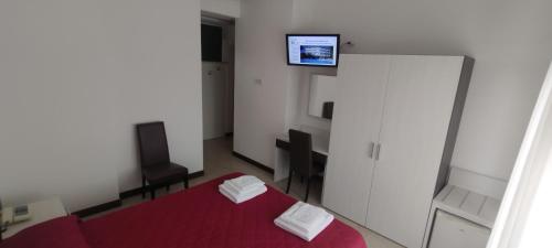 Ein Schlafzimmer mit einem roten Bett und einem Fernseher an der Wand. in der Unterkunft Hotel K2 in Numana