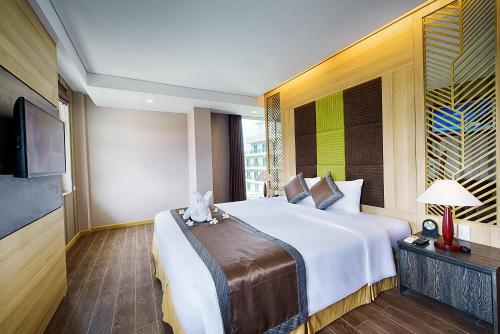 a hotel room with a large bed and a television at Muong Thanh Holiday Muine Hotel in Mui Ne