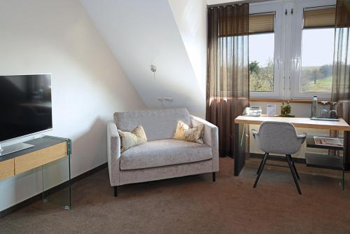 a living room with a chair and a desk and a television at Landhotel Hauer in Pleisweiler-Oberhofen