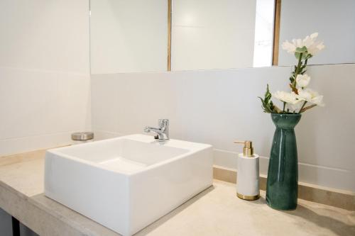 een badkamer met een witte wastafel en een vaas met bloemen bij 5- Fantastico duplex centrico! in Mendoza