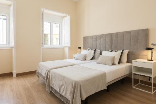 twee bedden in een witte kamer met twee ramen bij City Rooms - Amesterdao - Private room by HD in Faro