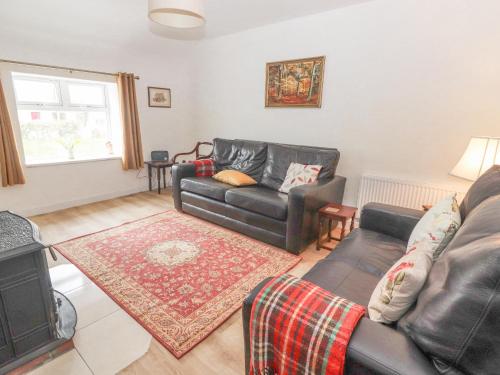 a living room with a leather couch and a fireplace at White Cottage in Abbeyfeale