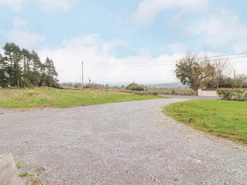 an empty gravel road with a grassy field at White Cottage in Abbeyfeale