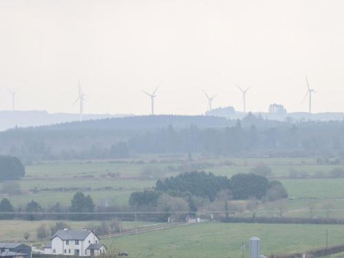 a house in a field with windmills in the background at White Cottage in Abbeyfeale
