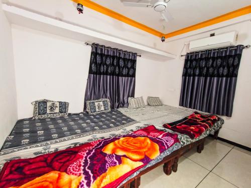 two beds in a room with black and red blankets at Bhavya Homestay in Garudeshwar