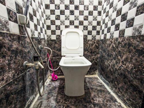 a bathroom with a toilet in a black and white tiles at Bhavya Homestay in Garudeshwar