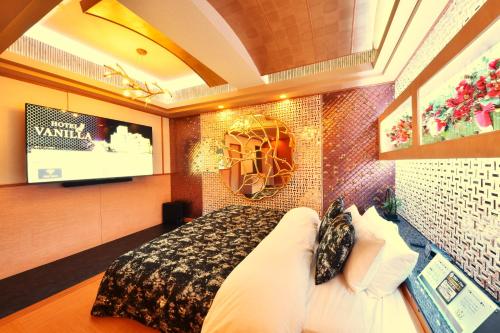 a bedroom with a large bed and a television at Hotel Vanilla Komaki (Adult Only) in Komaki