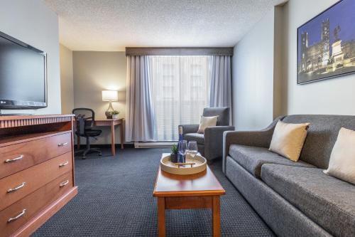 a living room with a couch and a tv at Hôtel Saint-Laurent Montréal in Montréal