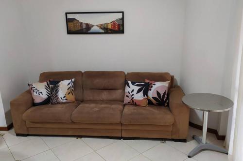 a brown couch with pillows and a table in a room at Apartamento 102 do Residencial Argonauta in Bombinhas