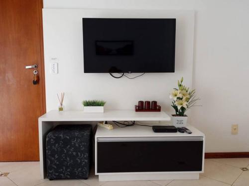 a white desk with a tv on a wall at Apartamento 102 do Residencial Argonauta in Bombinhas