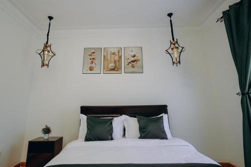 a bedroom with a bed with two lights above it at OREEKA COZY HOME in Kampala