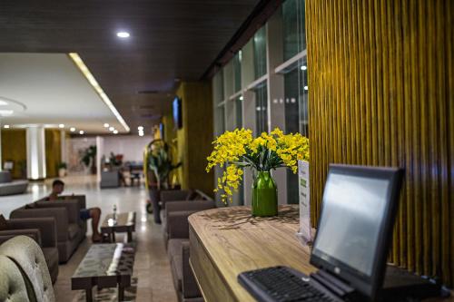 a desk with a laptop on a table with yellow flowers at Muong Thanh Holiday Muine Hotel in Mui Ne