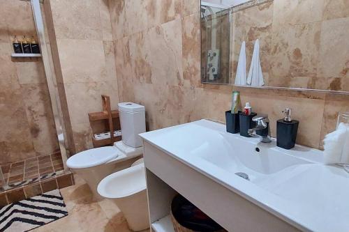 a bathroom with a white sink and a toilet at Moody & cozy 1br in city center in Luanda