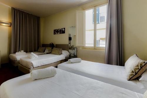 a hotel room with three beds and a window at Albergo Firenze in Florence