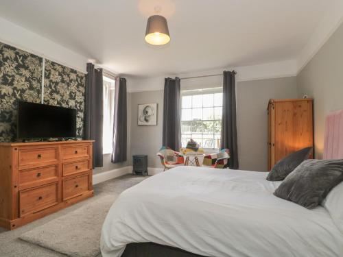 a bedroom with a bed with a television and a dresser at Buckland House Annex in Taunton