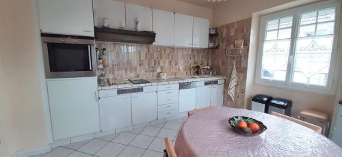 een keuken met een tafel en een fruitschaal bij L'Enclos des Lys -appartement in Aurillac