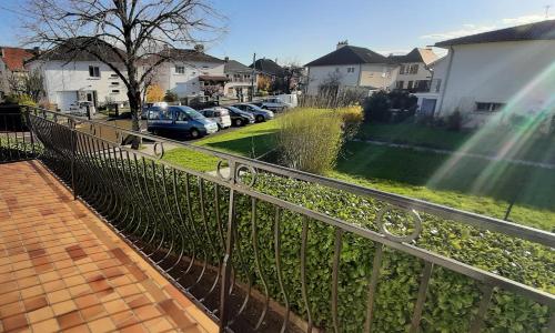 een hek naast een tuin met geparkeerde auto's bij L'Enclos des Lys -appartement in Aurillac