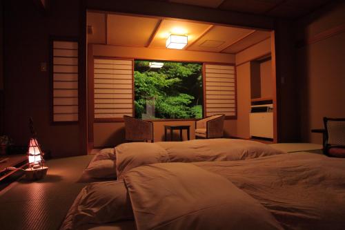 two beds in a room with a window and a table at Yumotokan in Agano