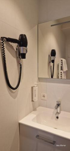 a bathroom with a sink and a phone on the wall at Hotel Des Zouaves in Koksijde