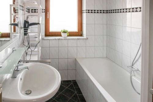 a white bathroom with a tub and a sink at Ferienwohnung zum Kunstei in Anger