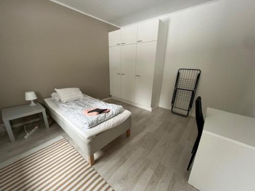 a white bedroom with a bed and a chair at Apartment Kuokkamaantie, Pyhäjoki in Pyhäjoki