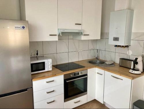 une petite cuisine avec des armoires blanches et un micro-ondes dans l'établissement Grand appartement proche Cité de l'Espace, à Toulouse