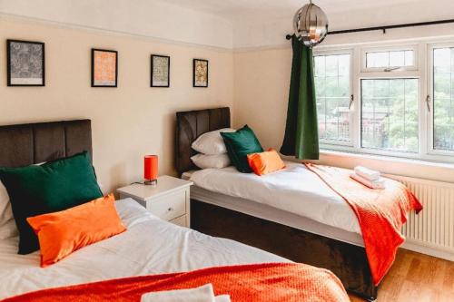 a bedroom with two beds with orange and green at Ilford - Driveway- 3 bed- M6 J6 Contractors & Families in Birmingham