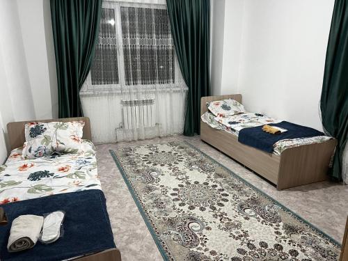 two beds in a room with a window and a rug at 3 комнатная квартира in Türkistan