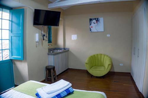 Cette chambre comprend deux lits et une chaise verte. dans l'établissement By Cao Rest House, à Bogotá