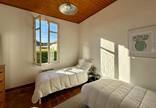 1 Schlafzimmer mit 2 Betten und einem Fenster in der Unterkunft Ferienhaus mit Garten im Herzen von Lacanau-Océan in Lacanau-Océan
