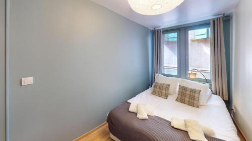 ein Schlafzimmer mit einem Bett mit Kissen und einem Fenster in der Unterkunft Le Tonnelier Strasbourgeois - Strasbourg Cathédrale in Straßburg