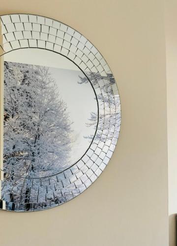 a mirror hanging on a wall with a tree in the reflection at All Seasons Bed & Breakfast - Adults Only in Weston-super-Mare