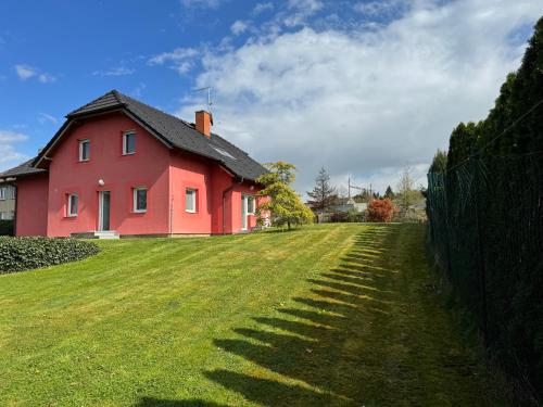 a red house on a green field with a fence at Dům Stašov in Stašov